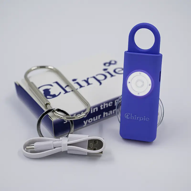 Cobalt blue Chirpie Link personal safety alarm with LED light activated, shown with keyring, USB charging cable, and retail packaging.